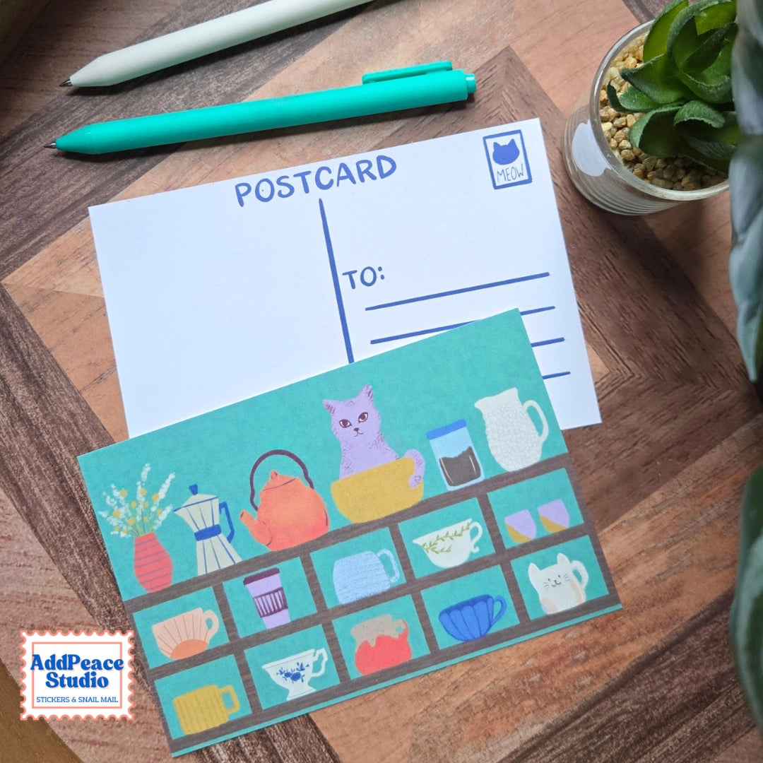 AddPeace Studio - Cats & Cups Postcard Pack
A charming illustrated postcard set for cat lovers, homebodies, and anyone craving a little analog joy. This Cats & Cups postcard pack celebrates quiet moments, warm drinks, and the simple pleasure of sending real mail. Designed for the current resurgence of snail mail, pen pals, and intentional connection, these postcards make it easy (and fun) to go offline on purpose.
Each set includes ten unique 4x6 postcards featuring original Cats & Cups illust