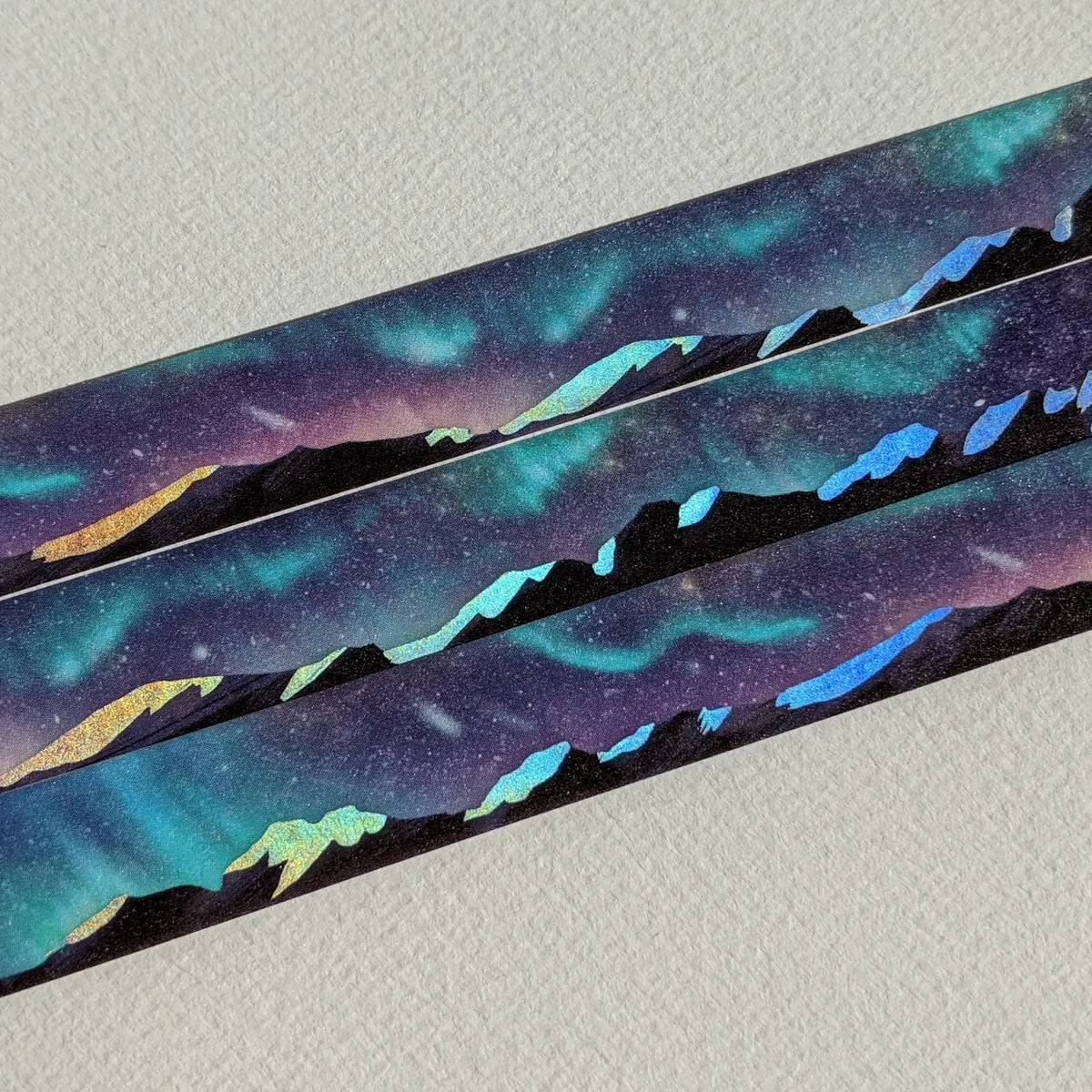AdrianSlothArt - Aurora Mountain Landscape Holographic Foil Washi Tape
Washi tape with holographic foil highlighting the snow on the mountains, reflecting the northern lights in the night sky.
Details:
15 mm x 10 m
holographic foil washi tape