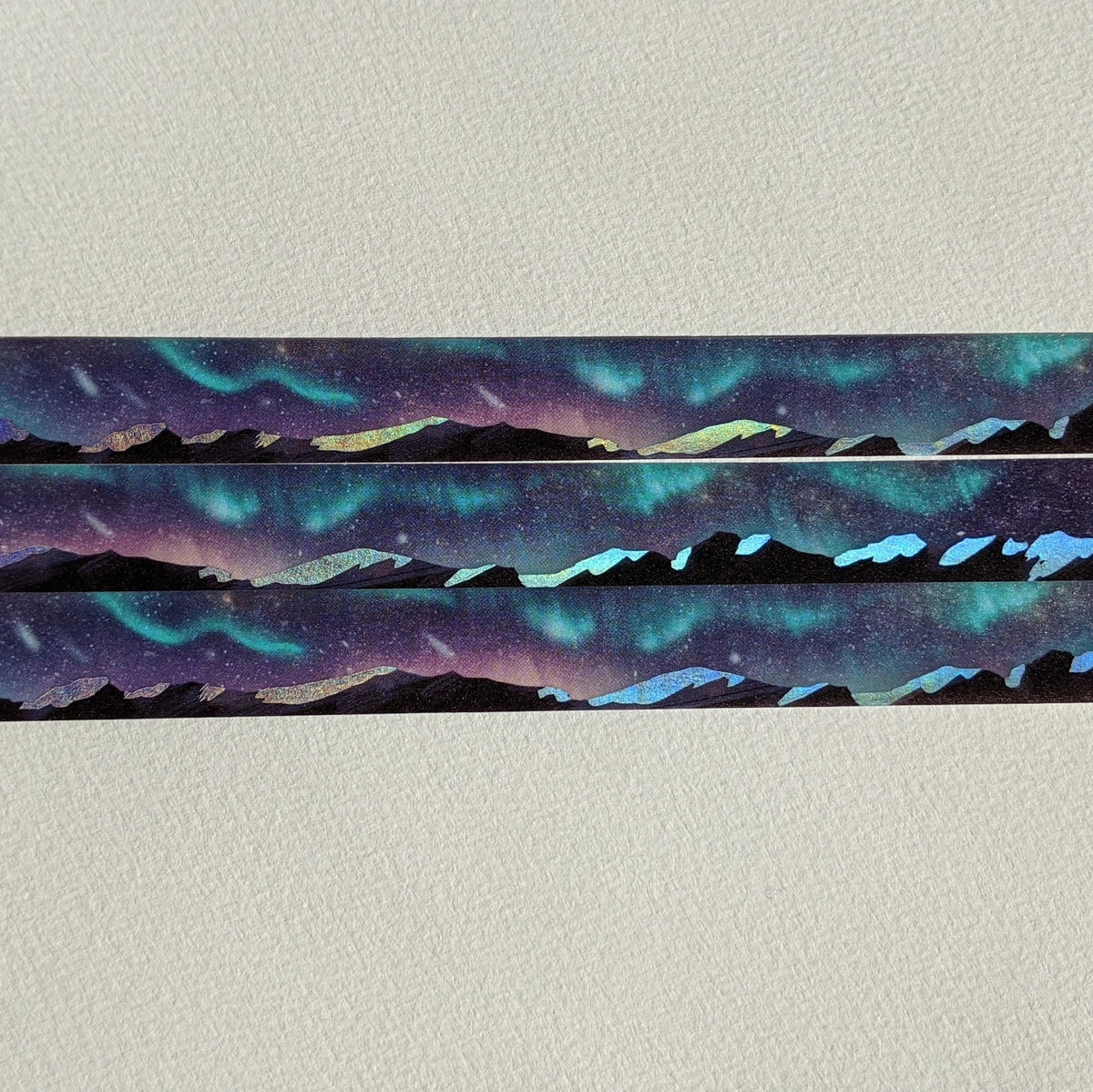 AdrianSlothArt - Aurora Mountain Landscape Holographic Foil Washi Tape
Washi tape with holographic foil highlighting the snow on the mountains, reflecting the northern lights in the night sky.
Details:
15 mm x 10 m
holographic foil washi tape