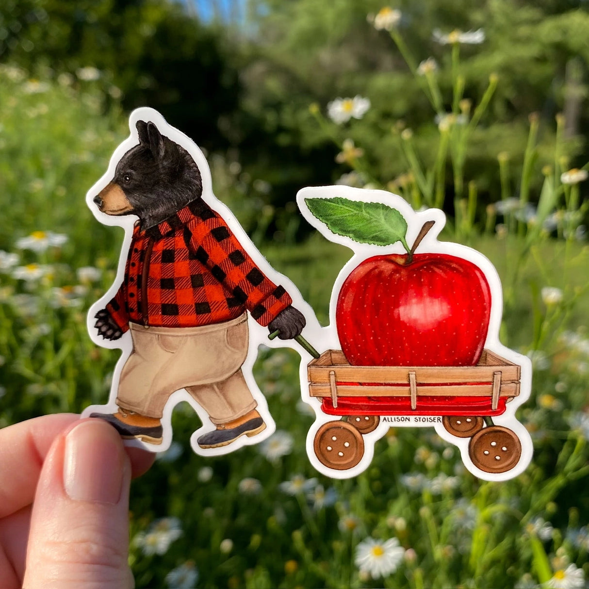 This flannel-clad American black bear is hauling a larger-than-life juicy red apple in his button-wheeled applecart. His family is no doubt polishing off some apple cider donuts while he does all of the hard work. Here's hoping they saved one for him!
This die-cut gloss vinyl sticker is durable, weatherproof, and perfect for water bottles, notebooks, laptops, bikes, and all sorts of other surfaces!
Make sure to clean and dry the surface thoroughly before applying.