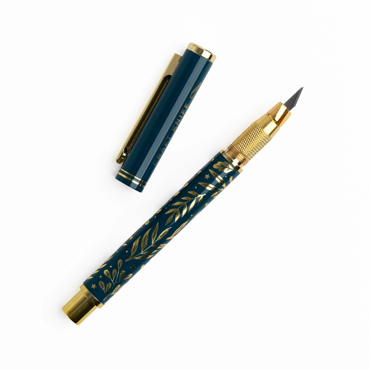 A beautifully designed craft knife featuring a deep teal barrel adorned with gold botanical detailing. With its precision blade and sturdy metal construction, this tool brings both function and elegance to journaling, scrapbooking, and detailed paper crafting.
Specs & Details:
Material: Metal body with gold accents
Design Theme: Teal barrel with gold botanical illustration
Blade: Precision craft blade (replaceable)
Features: Removable cap for safe storage, textured grip for control
Use: Ideal for cutt