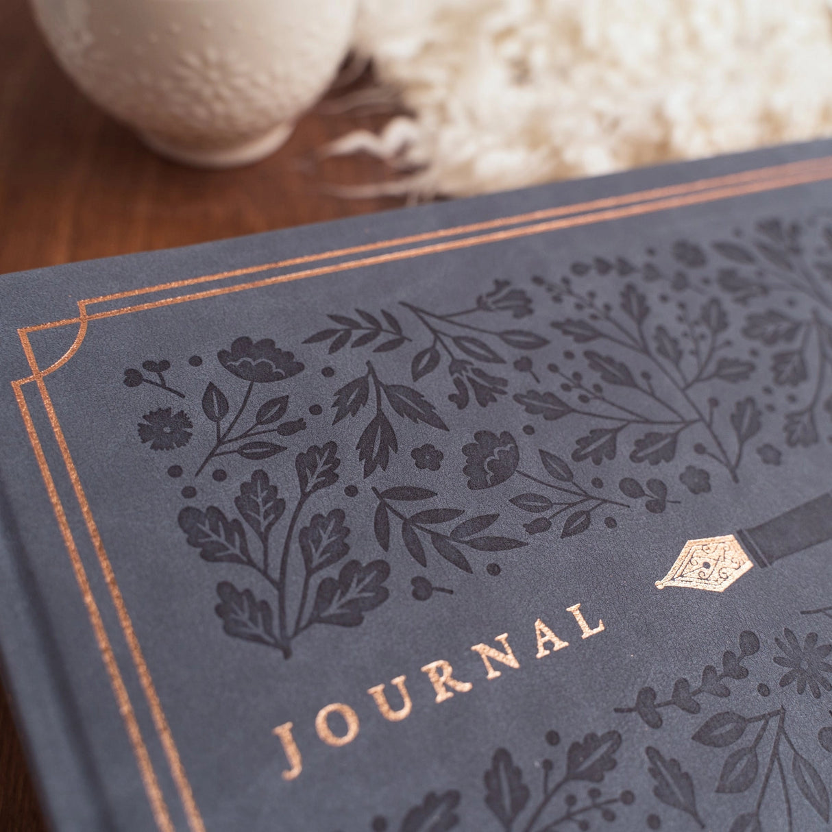 Introducing the Heirloom notebook. This Letter Sized notebook is truly special, featuring a unique full cover design. The intricate foliage pattern and fountain pen is debossed on a suede-like blue vegan leather cover, finished with a vintage rose gold stamping.
This notebook comes with the choice of Dot Grid or Lined pages, and is the perfect journal for a special occasion. From a memory keeping scrapbook to wedding gues