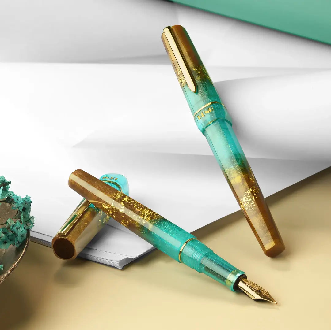 BENU presents the newest Haute Collection — a line of elegant, fashion-inspired pens that blend classic charm with bold, modern flair. The designs include both subtle and vibrant styles, showcasing BENU’s signature glitter and color artistry. Each pen features a faceted body with alternating wide and slender facets, complemented by either gold-plated or chrome-plated trims for a sleek, timeless look.
Seal and caramel tones swirl together, flecked with radiant gold. Lush evokes runway opulence — bold, textu