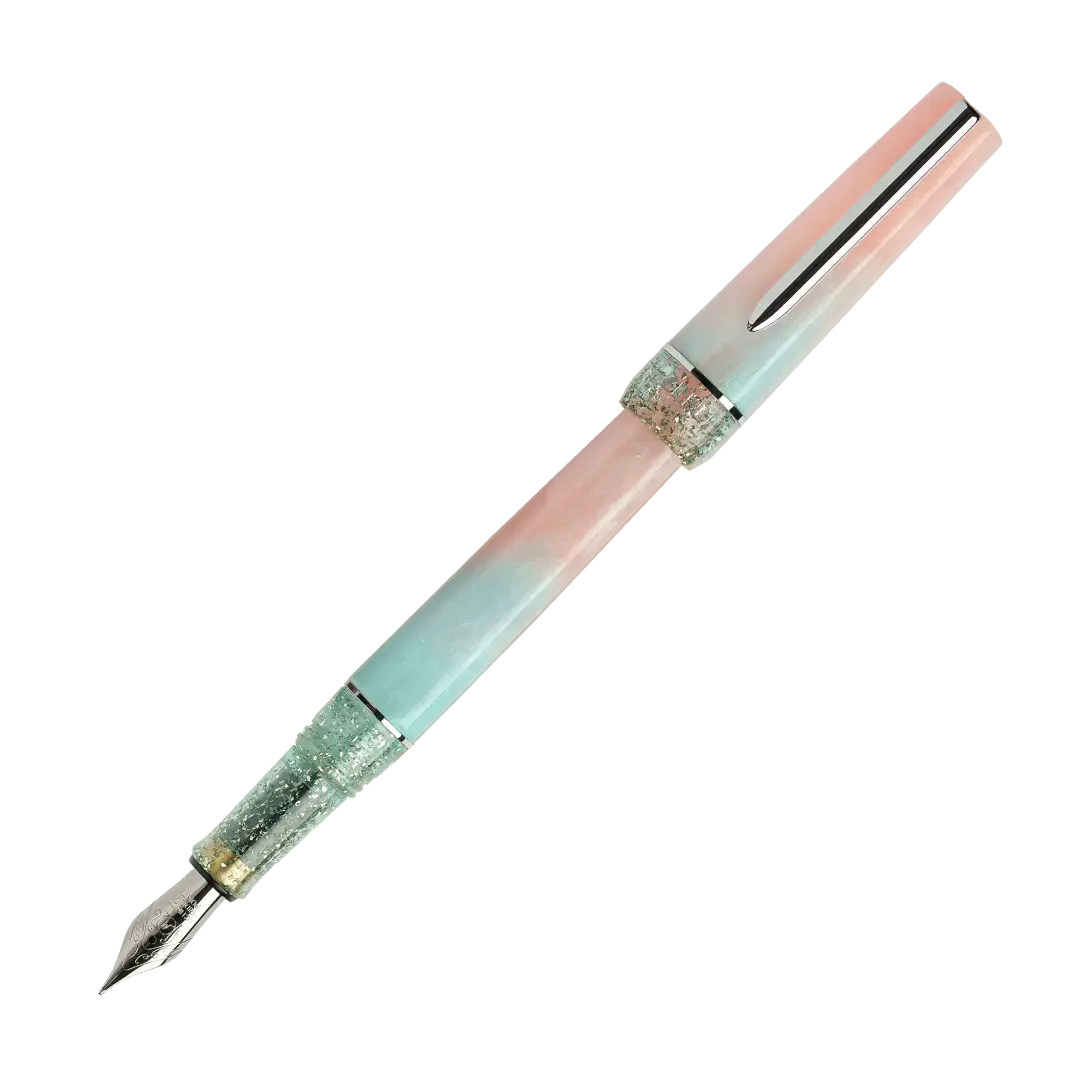 BENU presents the newest Haute Collection — a line of elegant, fashion-inspired pens that blend classic charm with bold, modern flair. The designs include both subtle and vibrant styles, showcasing BENU’s signature glitter and color artistry. Each pen features a faceted body with alternating wide and slender facets, complemented by either gold-plated or chrome-plated trims for a sleek, timeless look.
Soft shades of rose and mint melt together in Perle, accented by a sparkling band. As fresh as spring light