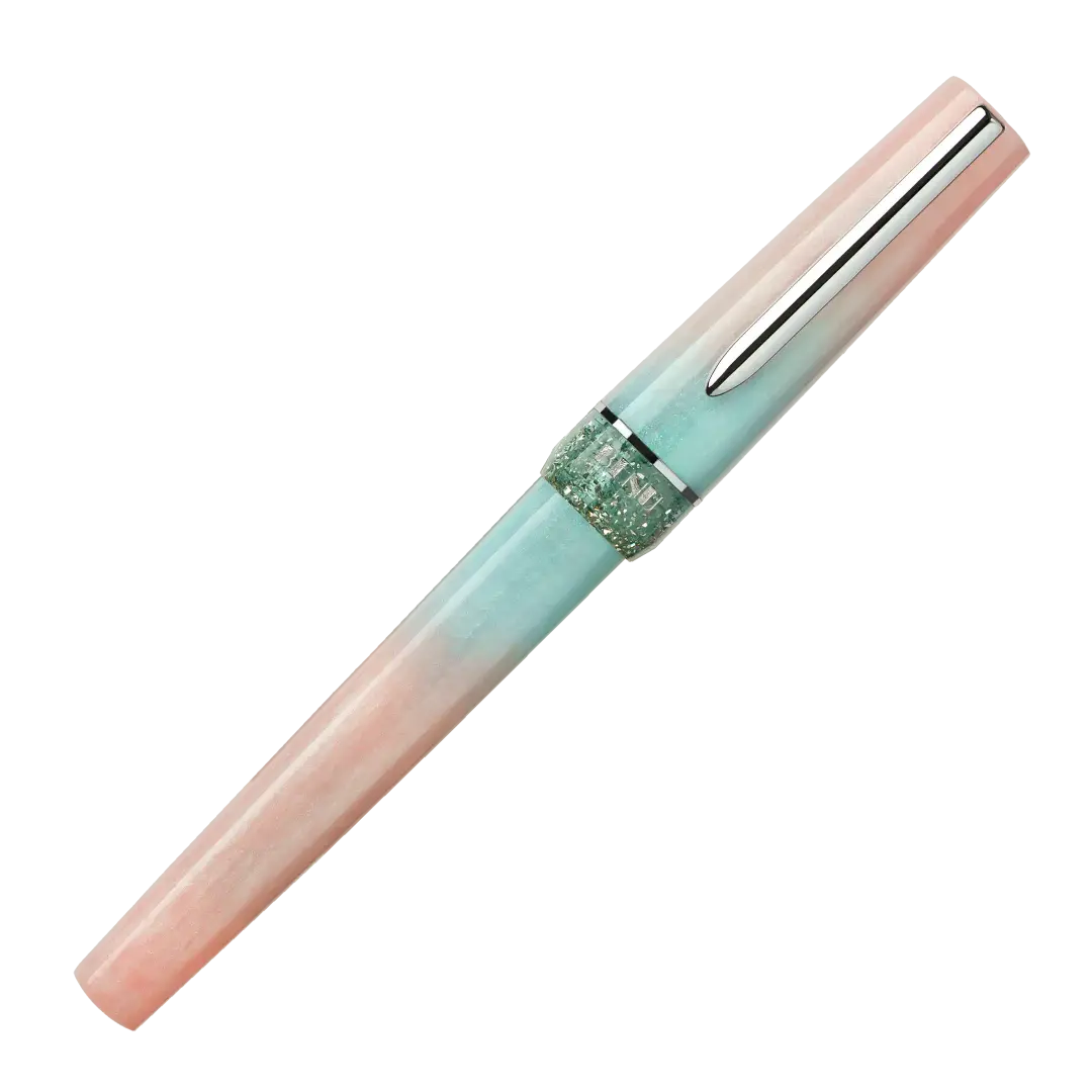 BENU presents the newest Haute Collection — a line of elegant, fashion-inspired pens that blend classic charm with bold, modern flair. The designs include both subtle and vibrant styles, showcasing BENU’s signature glitter and color artistry. Each pen features a faceted body with alternating wide and slender facets, complemented by either gold-plated or chrome-plated trims for a sleek, timeless look.
Soft shades of rose and mint melt together in Perle, accented by a sparkling band. As fresh as spring light