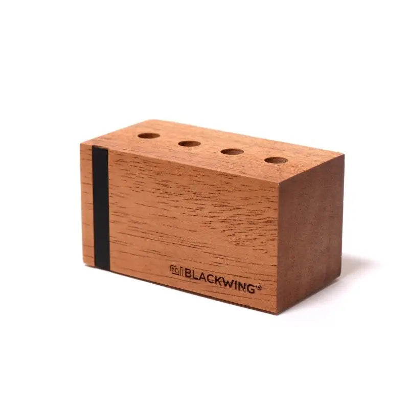 This solid wood pencil display is made with mahogany and is designed to showcase four upright Blackwing pencils. Display the four core Blackwing pencils, or choose four of your favorite designs to add some character to your desk. This display fits well on a desk or shelf, or you can hang it using the predrilled mounting holes. Blackwing logo engraved on the side.
The Blackwing Upright Four Pencil display measures 3.5 x 1.75 x 1.875 inches.
