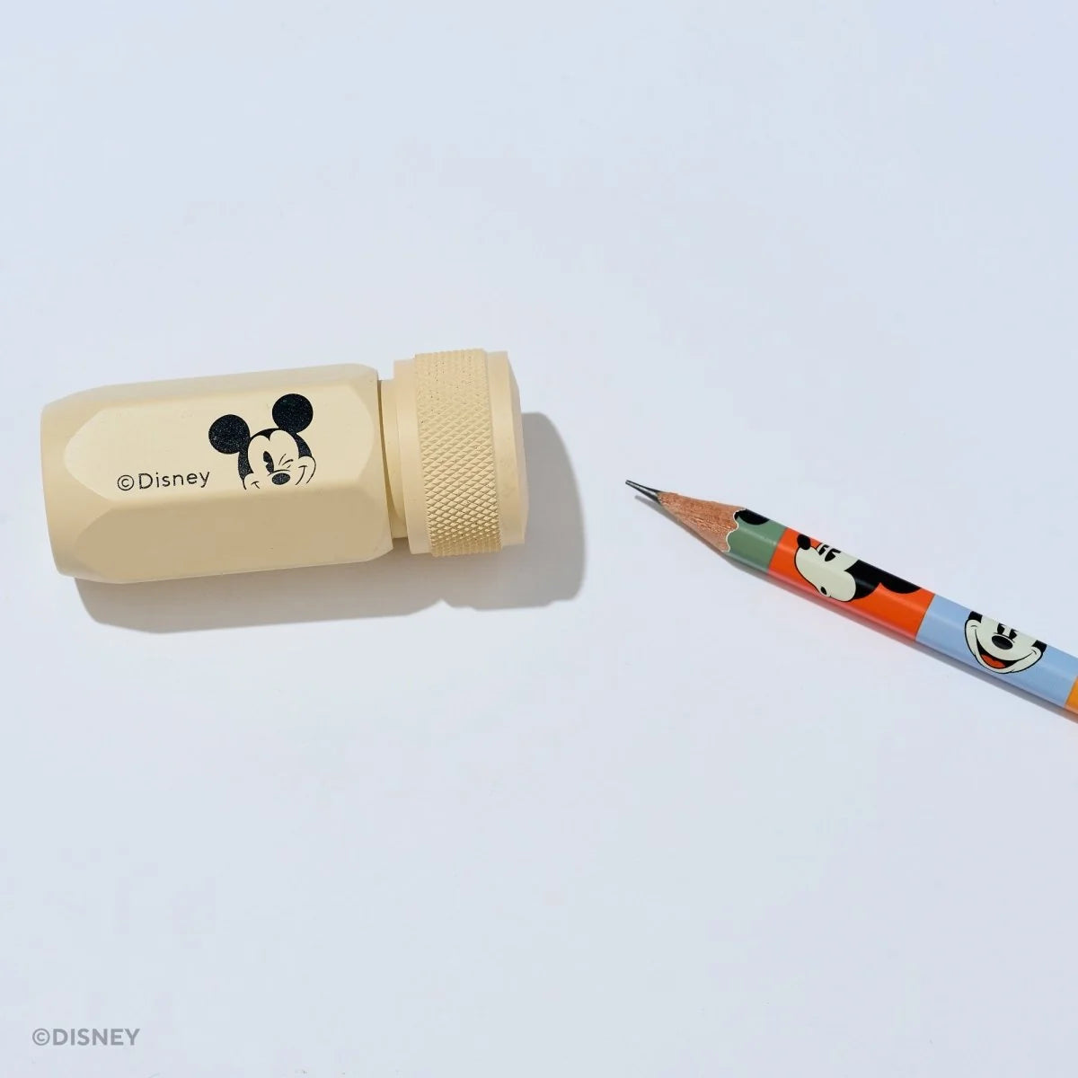 This premium pencil sharpener is made of machined aluminum and sharpens your pencils to a strong, curved point. The cream-colored sharpener features a Mickey Mouse illustration and printed Disney logo on the side in black.