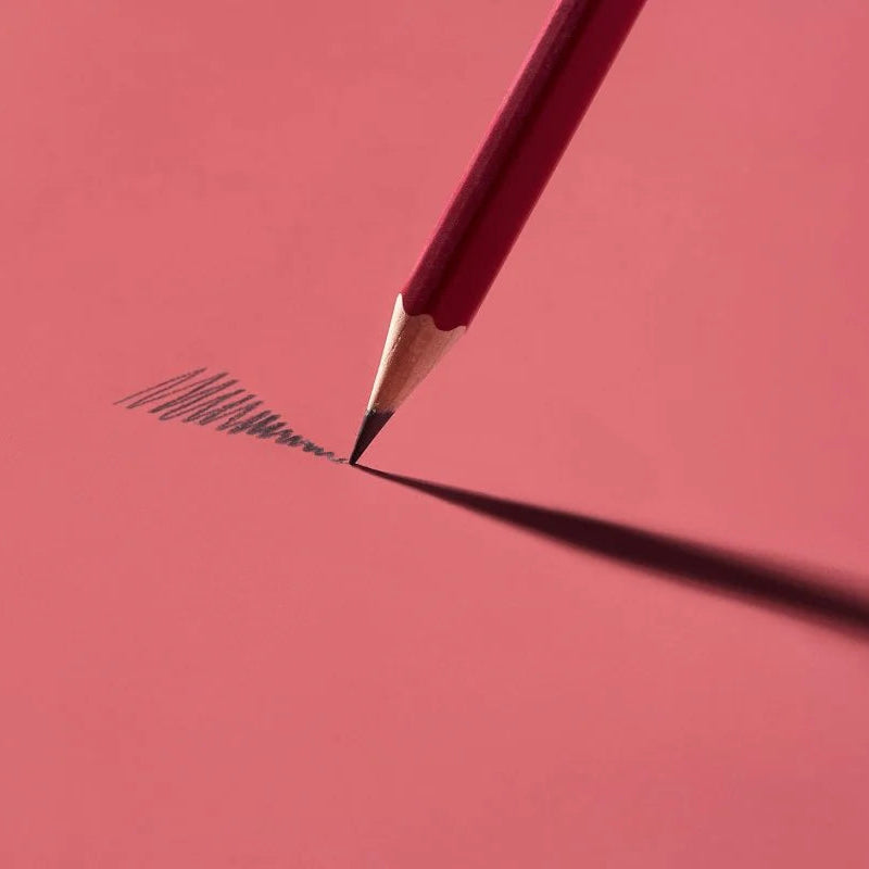 This colorway has a matte red finish, copper imprint, copper ferrule, and light gray eraser. It features a “SOFT” pencil graphite indicator stamp on the barrel. Not to be confused with our red core pencils, this is a graphite pencil with a red barrel. This pencil is ideal for musicians, woodworkers, and anyone who prefers a soft, dark graphite line. The Blackwing Matte is the softest of the four core Blackwing models.
Blackwing Matte pencils come in a 12-pack gift box that also doubles as a pencil cup. The