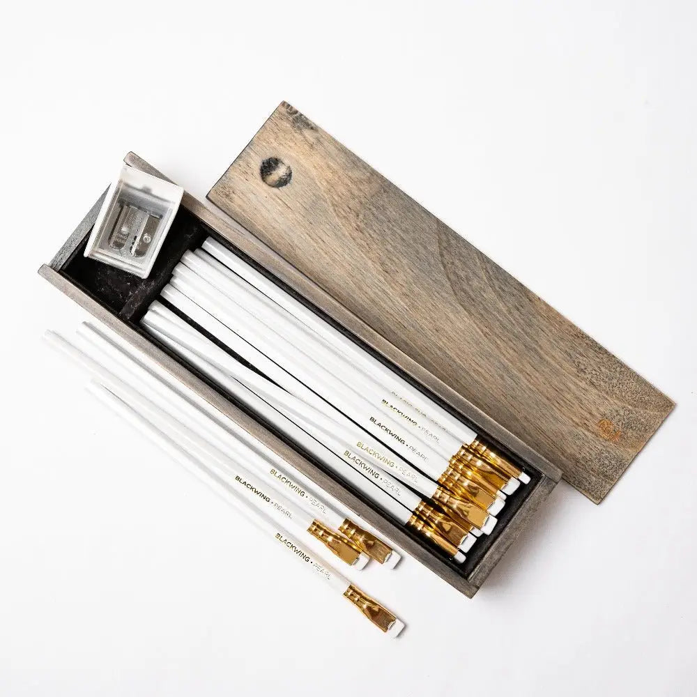 The Blackwing Rustic Box features your choice of 12 premium Blackwing graphite pencils and our reliable Two-Step Long Point Sharpener. Choose from 12 Matte pencils,12 602 pencils, 12 Pearl pencils, 12 Natural pencils, or 3 of each. The aged pine pencil box slides open to reveal the Blackwing pencils and a black cork-lined interior. The smooth stationery box is perfect for any workspace, office, or desk.
All Rustic Boxes now come with our Grey Two-Step Long Point Sharpener.
All Blackwing pencil products co
