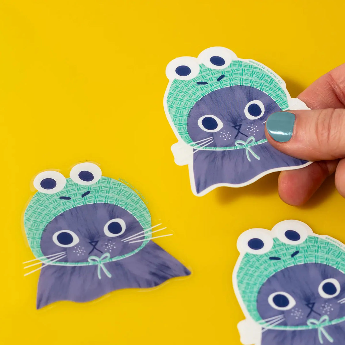 Bromstad Printing Co. - Frog Hat Cat Clear Vinyl Sticker
Can a cat croak? This kitten might! He wears a cozy knitted frog hat atop his cute kitten head. This 3" clear sticker is purrfect for adorning water bottles, laptops, and more. Drop one in an envelope along with a card as a little treat.
Waterproof
3x3