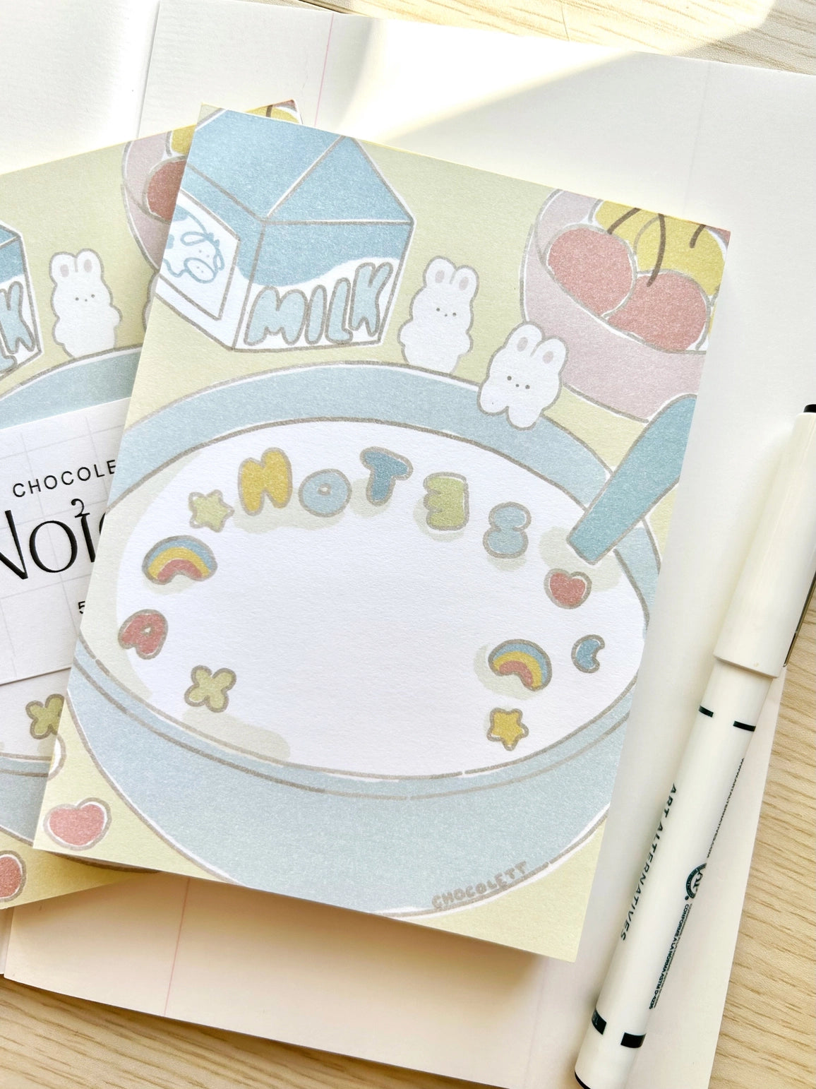 Chocolett - Cereal Memo-Pad
This memopad comes with 50 thick pages and measures 5.5 x 4 inches big. It’s cutely decorated with a little breakfast cereal scene and tiny bunnies.
Please note that these are not sticky notes.