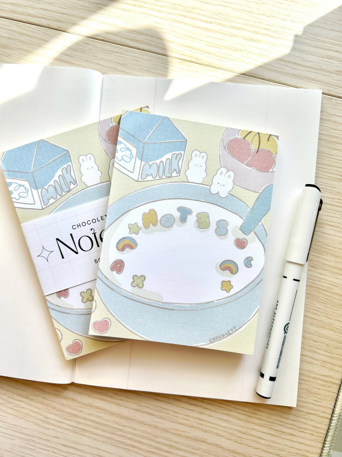 Chocolett - Cereal Memo-Pad
This memopad comes with 50 thick pages and measures 5.5 x 4 inches big. It’s cutely decorated with a little breakfast cereal scene and tiny bunnies.
Please note that these are not sticky notes.