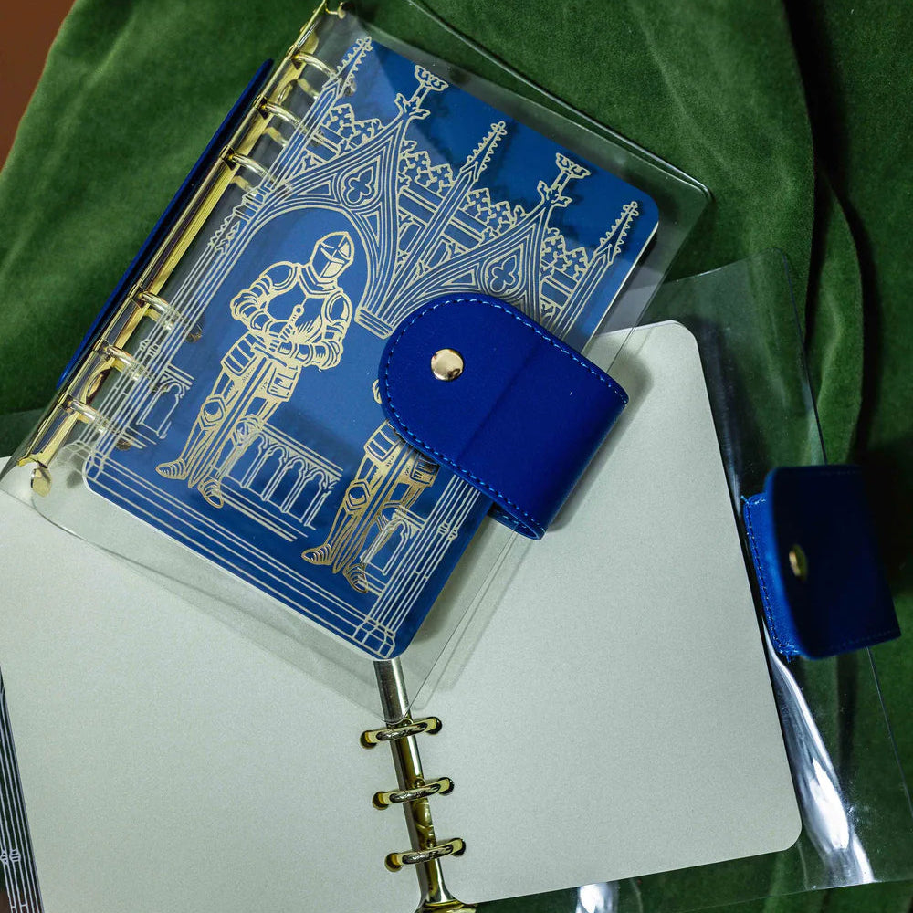 Step into a world of medieval wonder with this charming A6 binder notebook. Adorned with gothic architecture and noble knights rendered in shimmering golden foil, the cover transports you straight to a castle's grand halls.
Inside, a delightful coloring front page invites your creative touch, while 50 pages of luxurious cream 100 gsm paper await your thoughts, sketches, and stories. Perfect for journaling, note-taking, or artistic pursuits with a touch of enchantment.