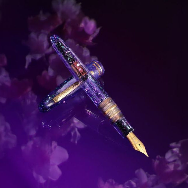 Esterbrook x Sakuradragon Sakura Street Estie Fountain Pen
Created with artist Cindy Duong of Sakuradragon, the Sakura Street Estie brings her imaginative illustrated world to Esterbrook's traditional Estie fountain pen. Its U.S.-blended material combines translucent purple with colorful glitter sparkle, while the custom clip is etched with Cindy's Sakura pattern. Dual Esterbrook and Sakuradragon engraving and a gold-plated converter finish the design. Each pen arrives in special packaging with Japanese gi