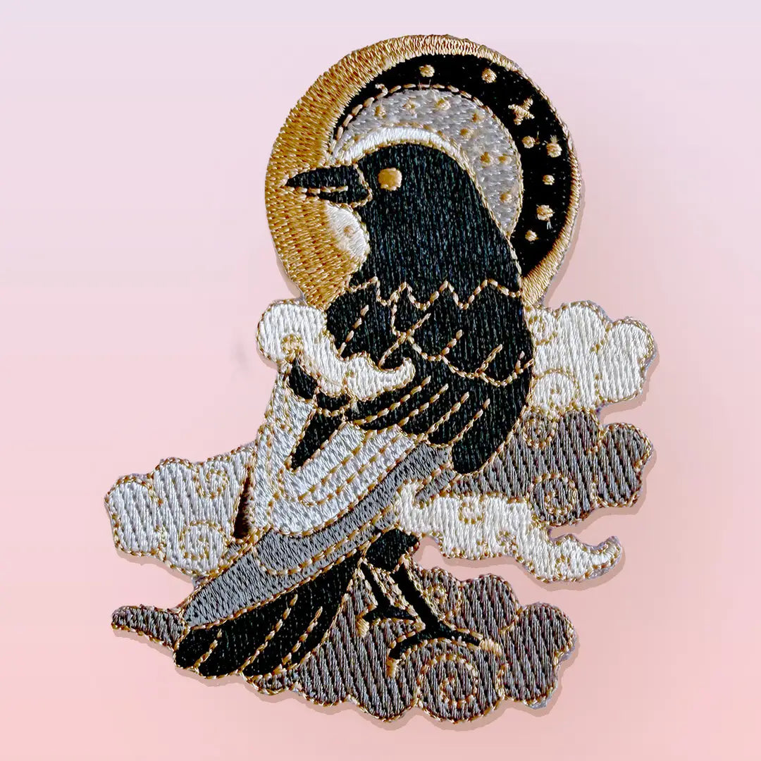 This fabulous patch features a black crow surrounded by grey glittery clouds, and a starry moon with grey backgrounds.
Beautifully woven with black, white, grey & gold threads, this fabulous patch with brighten up any coat, bag or hat!
Measurements: 70mm x 90mm