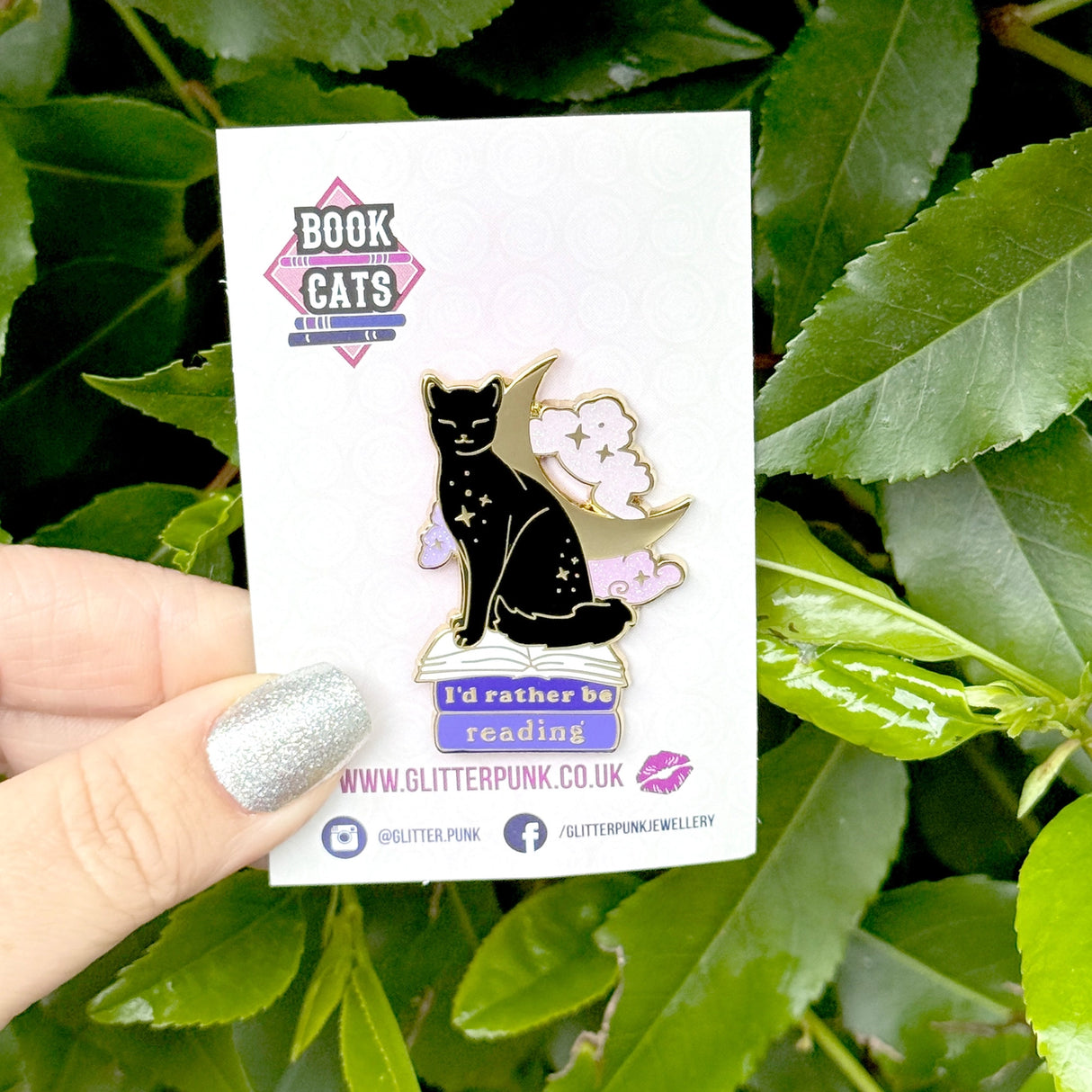 We’ve all sometimes wished we were at home with a hood book, rather than having to deal with the real world! This super cute pin features a black cat sitting on pink & purple books with the slogan ‘I’d rather be reading’. Behind the cat is a large crescent moon and a pair of glittery pastel clouds.
Measurements: 45mm (1.77”)