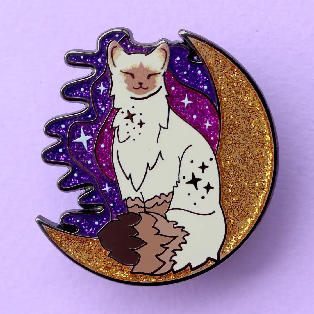 Calling all owners of a long haired pointed / meezer cats! This super cute design features the cat sitting in front of a sparkly moon with a glittery, starry sky in the background.
The pin is 40mm (1.57”) tall, and is made from gunmetal hard enamel, with glitter and UV printed details. It's secured with 2 pink clutches to keep the pin in place.