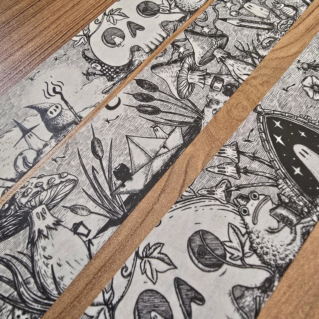 A unique and infinitely repeating fantasy landscape of melancholy oddities and curious characters, from original hand-drawn ink artwork by Jon Turner, recreated with incredible detail at miniature size in this washi tape that invites you to find new tiny details with every viewing.
This is a special extra-wide washi tape, 30mm high which really brings out all the tiny details. perfect for creating a decorative border when journalling, or for packing parcels with surreal style. 10m long.
