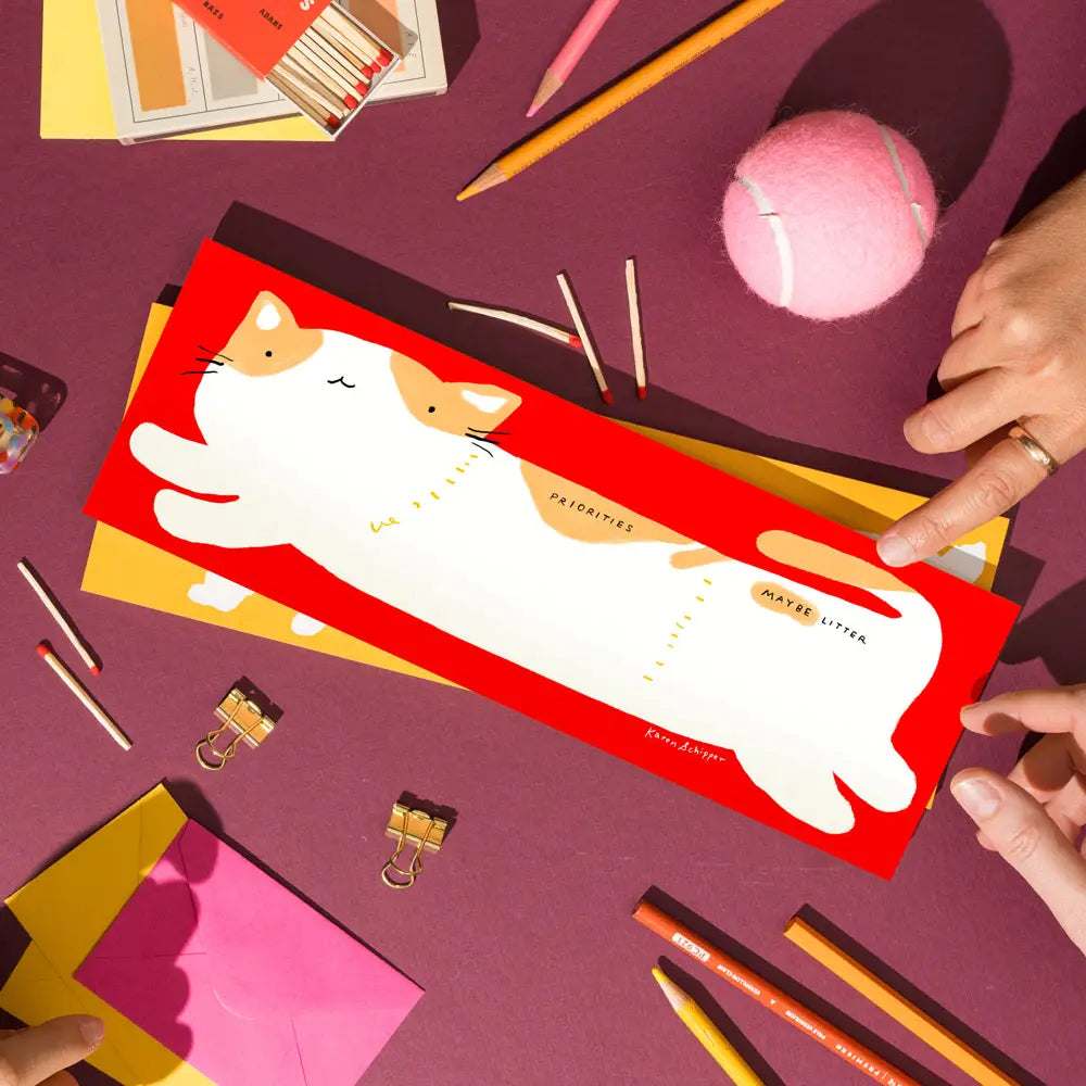Karen Schipper Weekly Desk Planner - Cooper Cat
Planning doesn’t have to feel serious. Cooper Cat Desk Planner is a cat desk planner pad featuring a chubby white cat stretched across a bold red background with the playful sections “Priorities” and “Maybe Later” — a cute cat planner that instantly catches attention.
It comes with 52 undated sheets, enough to last you the year.
Professionally printed full color
Size: 11.75 x 4.25 inches
52 tear-off sheets with cardboard backing
Packaged in plastic sleeve an