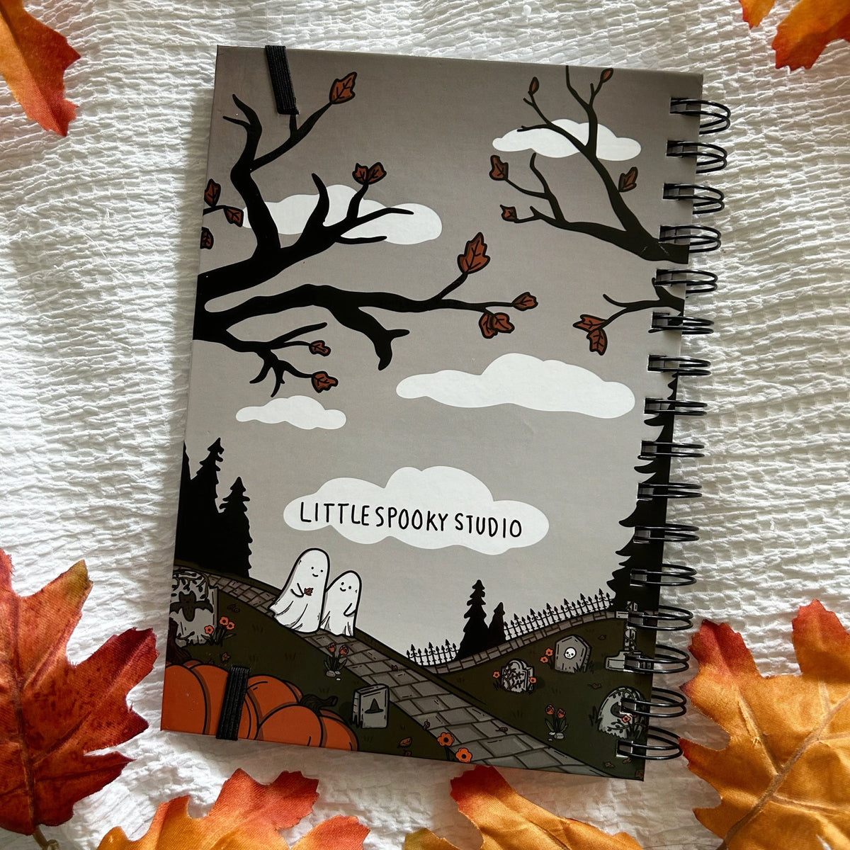 A new A5 notebook featuring ghosties strolling through the cemetery!
This hardcover notebook comes lined and with an elastic band. There are 96 double sided pages.