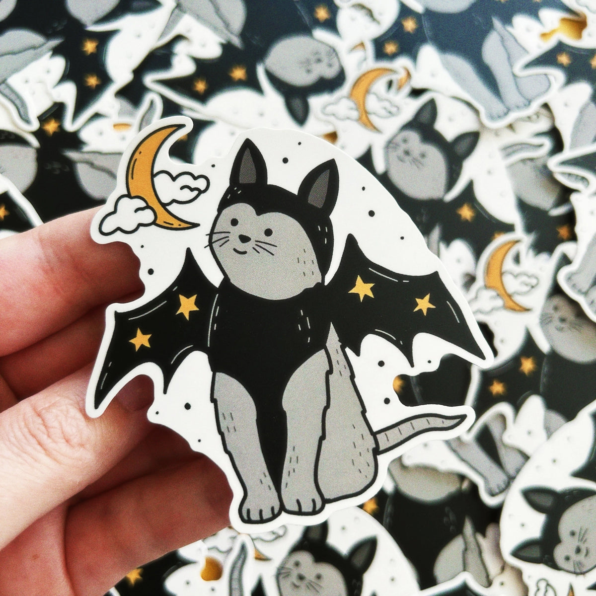 Little Spooky Studio - Vampire Cat Vinyl Sticker
A gray cat wearing vampire wings and matching hat with stars!
