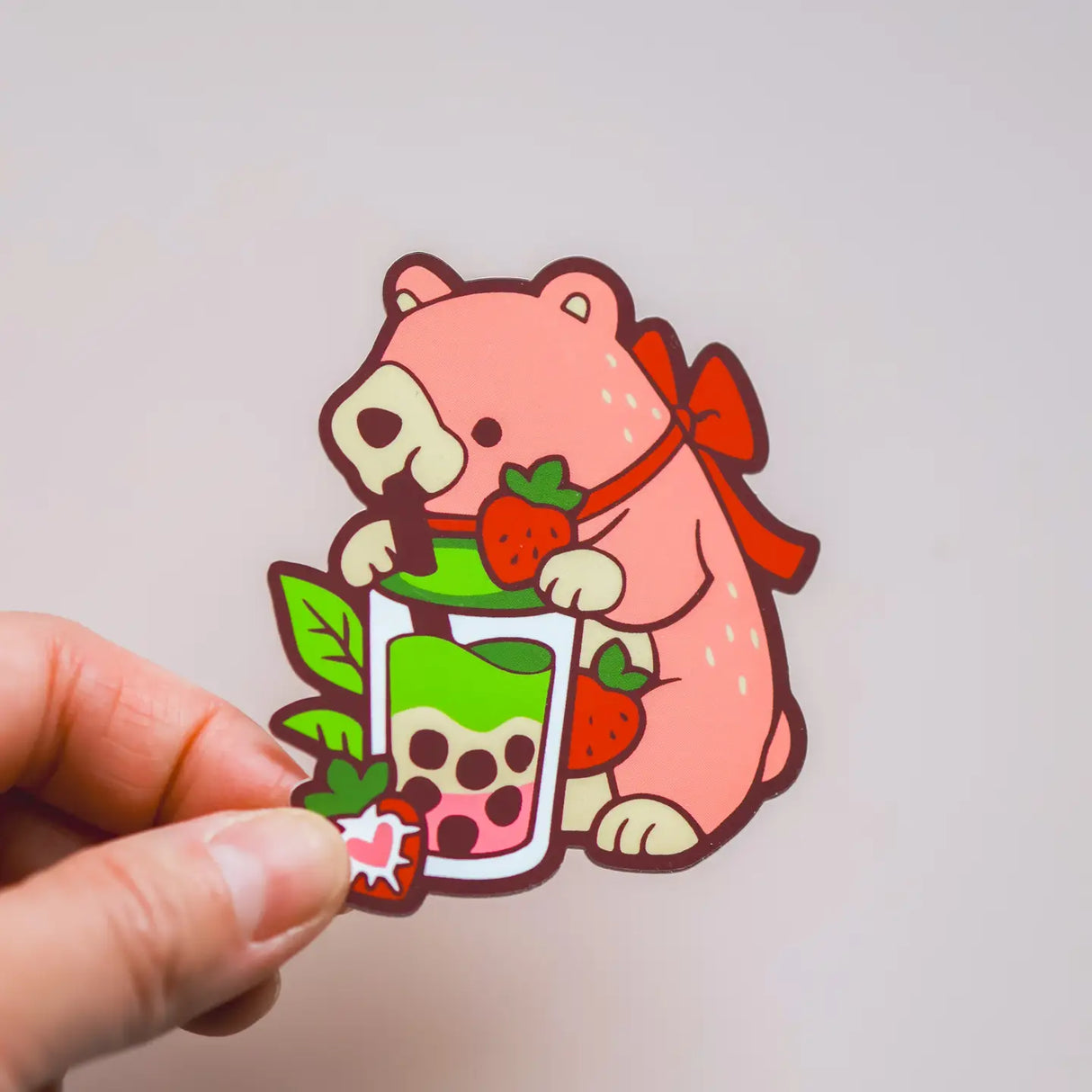 Cartoon bear holding a bubble tea with a hand on a light gray background