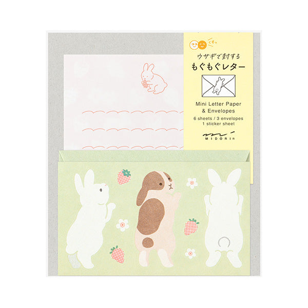 The set shows a rabbit stretching and chasing a strawberry. The stationery paper is a soft pink color inspired by strawberries. The ruled lines are designed to evoke the image of a rabbit bouncing around.