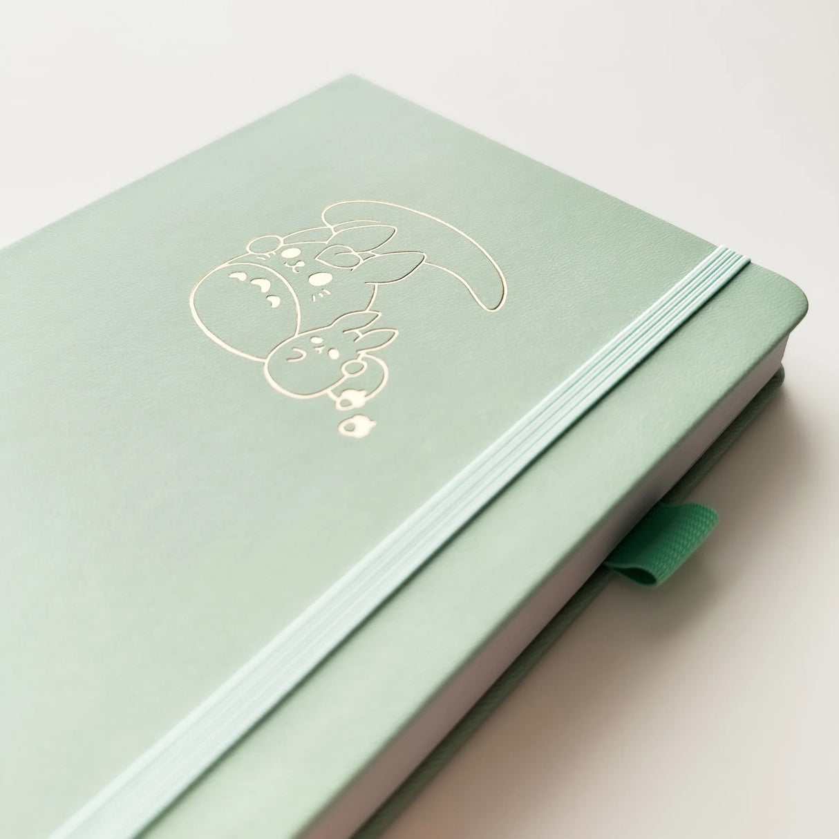 Bunny Spirit Journal in Sage Green with Gold Foil Logo🌱
Product Details:
Size: A5 (5.70 x 8.26 inches)
160 Dotted Grid Pages (5 x 5 mm)
2 Bookmarks
Elastic Band and Pen Holder
Expandable storage compartment