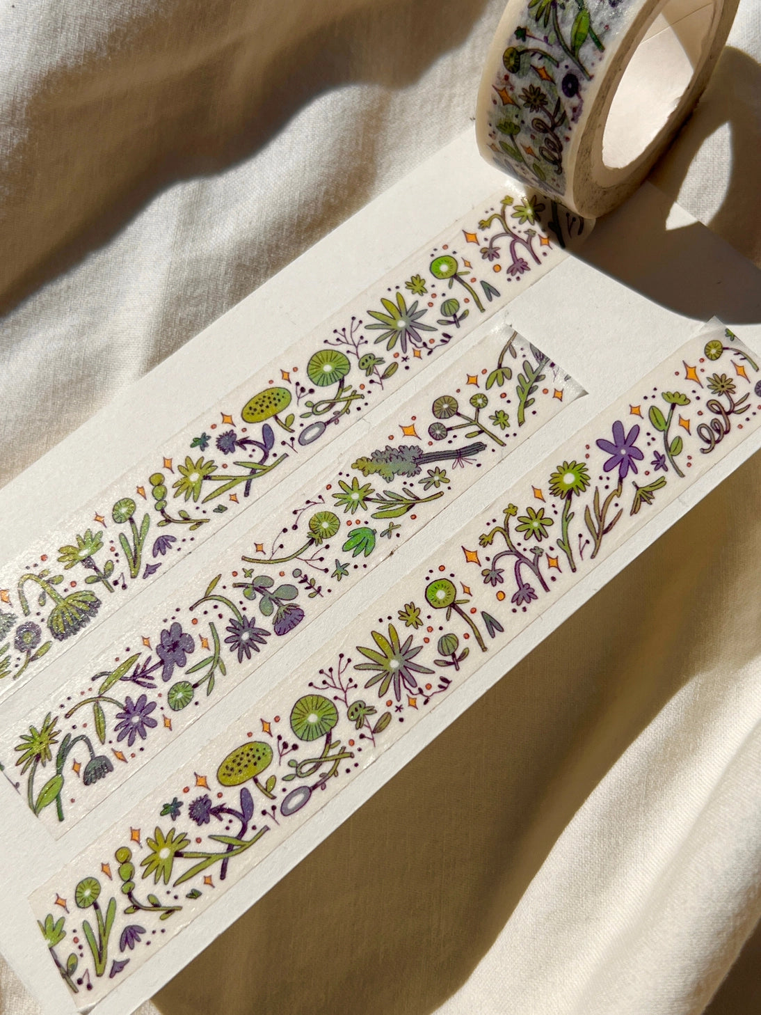 This washi tape features fluid green and purple flowers dancing loosely around to create an energetic, yet soft tape.
This roll is 15mm wide x 10m of paper tape. Washi tape is super durable and flexible. It tears easily and can be safely applied to a variety of surfaces; it doesn’t leave a sticky residue behind, making it especially ideal for stationery and hanging prints temporarily.