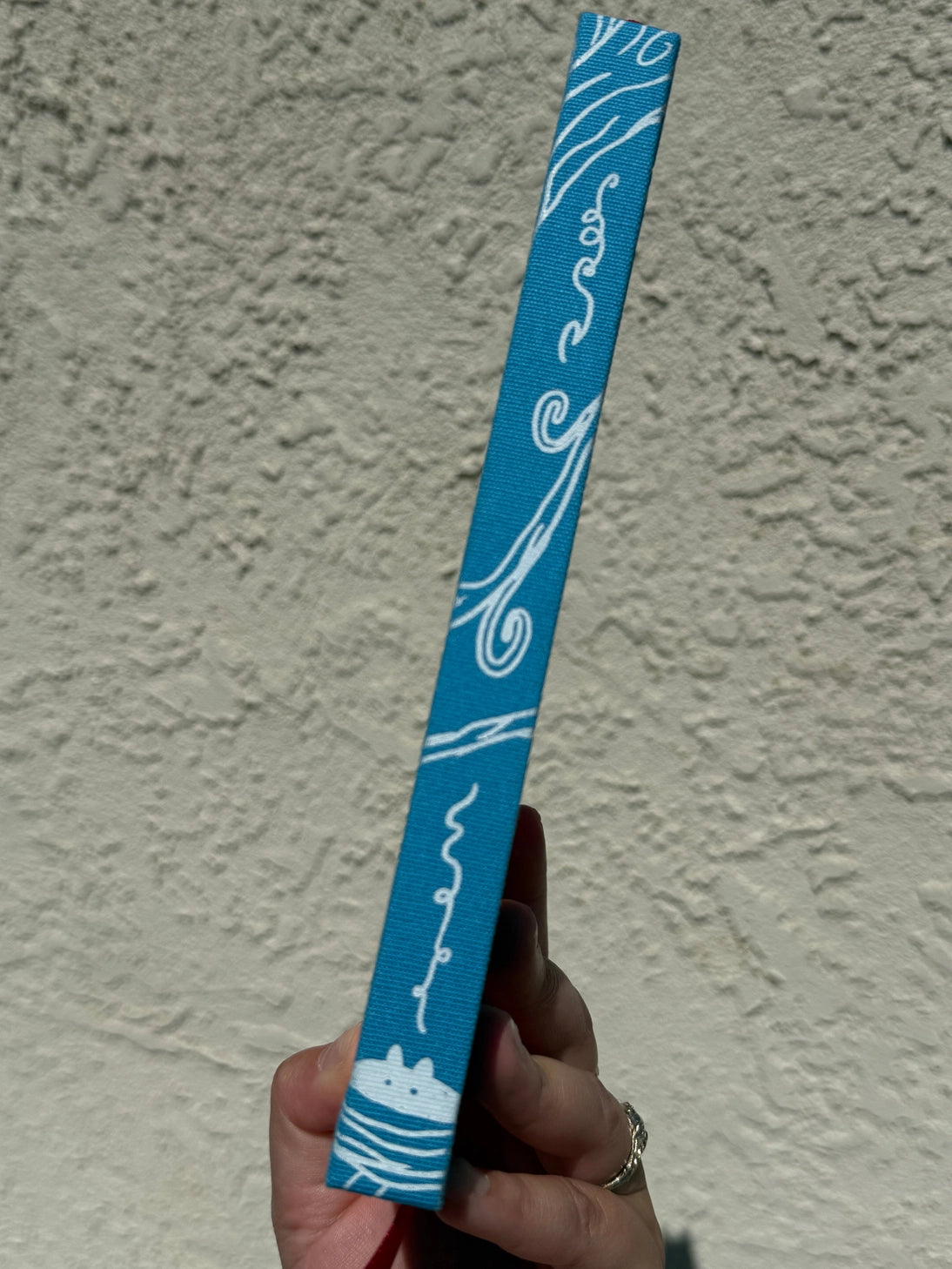 This is a blank 200 page notebook/sketchbook with thin ivory Munken paper perfect for light sketching or writing. Part of a fantasy collection called Woodfolk.
The cover is fluorescent pink/orange and has a smooth matte finish with gold foiling on the front and back. Plus it has a blue fabric spine with white embossing, adding to the charm of the book. Best for pencils, light pens, and generally light mediums, as thick markers or water can bleed. Not recommended for gouache or heavy marker use.