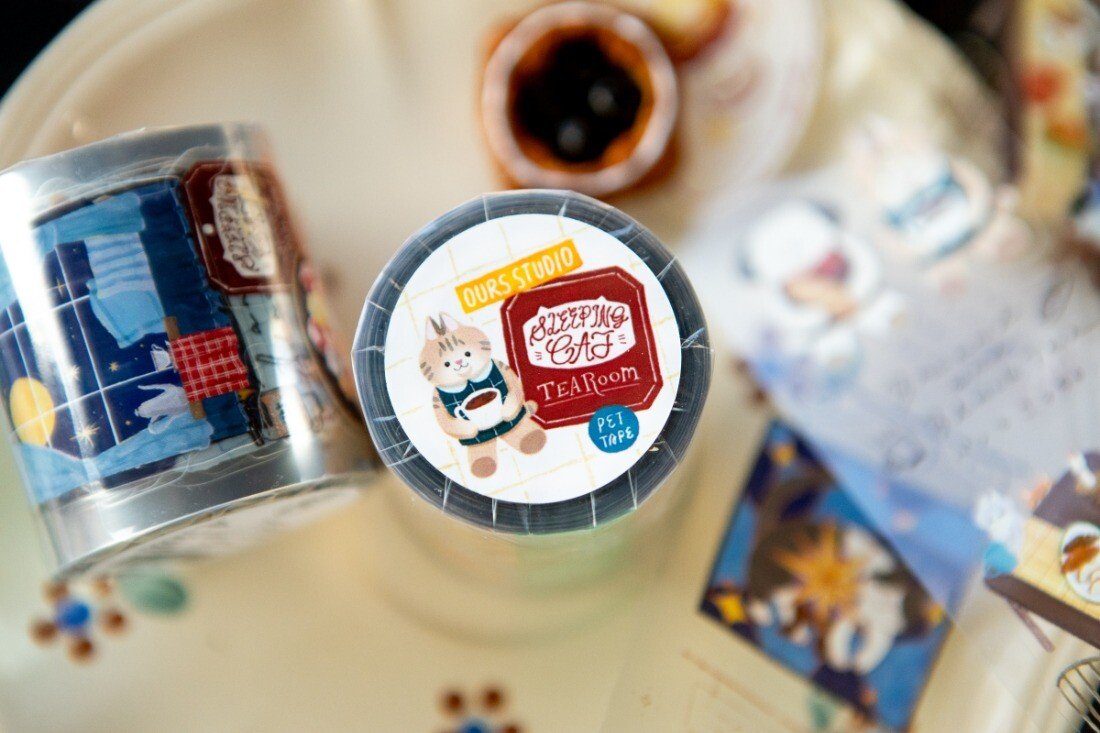 Welcome to the Tea Room! This kiss-cut PET Tape features a relaxing teahouse filled with cats and other furry friends. It adds the perfect touch of warmth to your journal pages with hints of golden brown and dark blue as conversations continue until midnight.