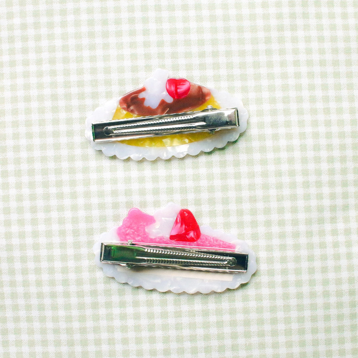 Pudding & Cake Hair Clips as a set of two clips. Clips are 2.5 inches long, made of acetate and have an alligator style clip on the back.
Clips should not be submerged in water.
Hair clips come with a backing card in a plastic sleeve.