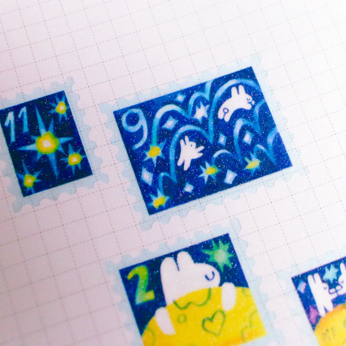 'To the Moon & Back' Frosted Glitter Transparent A6 Sticker Sheet. Stickers are stamp shaped and have a clear blue background.
Not waterproof.
Do not place in areas of high wear (laptops, phone cases, water bottles, etc).
Sticker sheets come packaged in a plastic sleeve.