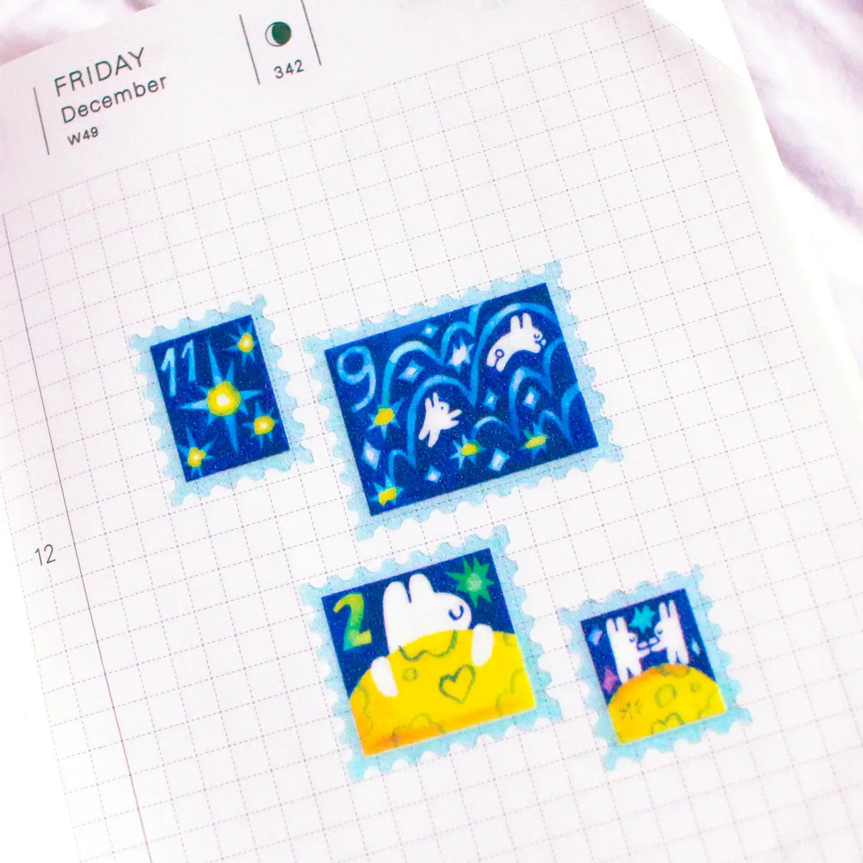 'To the Moon & Back' Frosted Glitter Transparent A6 Sticker Sheet. Stickers are stamp shaped and have a clear blue background.
Not waterproof.
Do not place in areas of high wear (laptops, phone cases, water bottles, etc).
Sticker sheets come packaged in a plastic sleeve.
