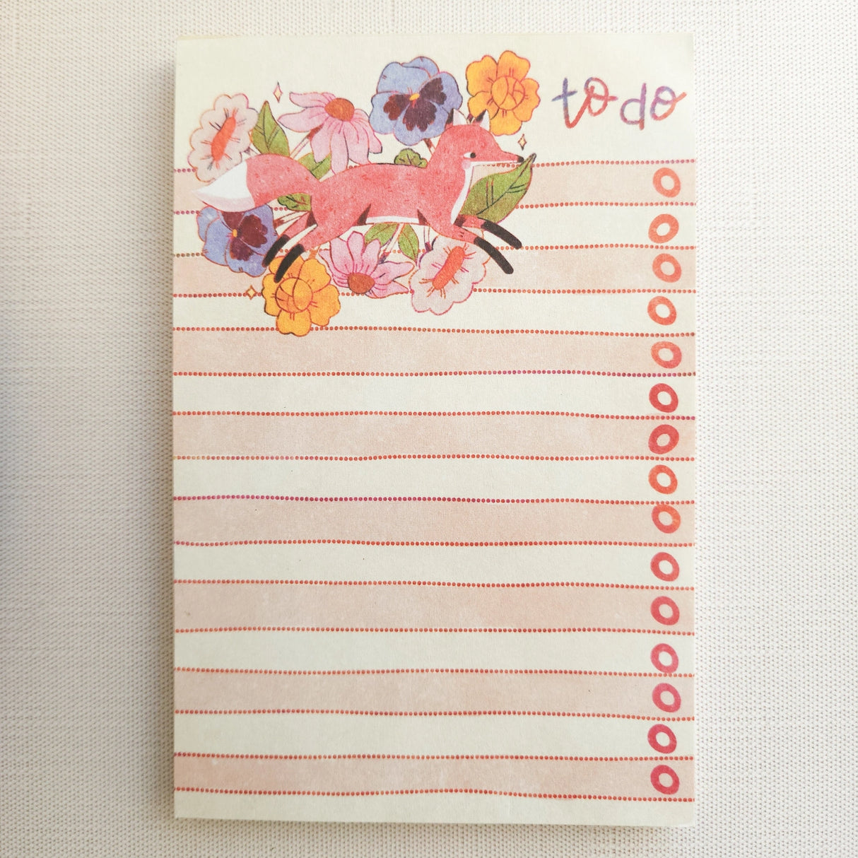 In a quiet clearing of Wildflower Woods, a fox moves through blooming flowers, petals lifting gently as he passes beneath open sky. This notepad brings that playful, woodland moment to your desk, making everyday lists feel a little more inviting.
Designed to be practical without feeling busy, this notepad offers a simple, cheerful way to keep track of daily to-do lists and planning.