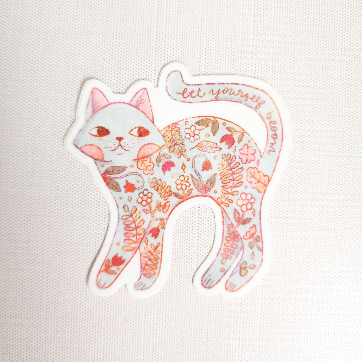 A calm cat returns from the blooming meadows of Wildflower Woods, patterned with flowers gathered along the way. This vinyl sticker captures that quiet, reflective moment, carrying a simple reminder to let yourself bloom.
Made from durable, waterproof vinyl, this sticker is designed to hold up wherever you place it—whether that’s a water bottle, laptop, or journal you reach for daily.