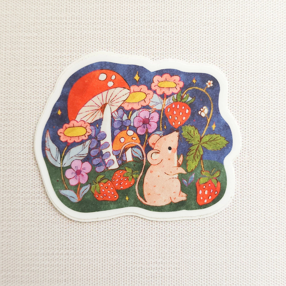 A cheerful little mouse pauses along a sunny garden path in Wildflower Woods, holding a ripe strawberry close before continuing on its way. This vinyl sticker captures that small, joyful moment, celebrating the simple pleasures tucked into everyday life.
Made from durable, waterproof vinyl, this sticker is designed to hold up wherever you place it—whether that’s a water bottle, laptop, or journal you reach for daily.