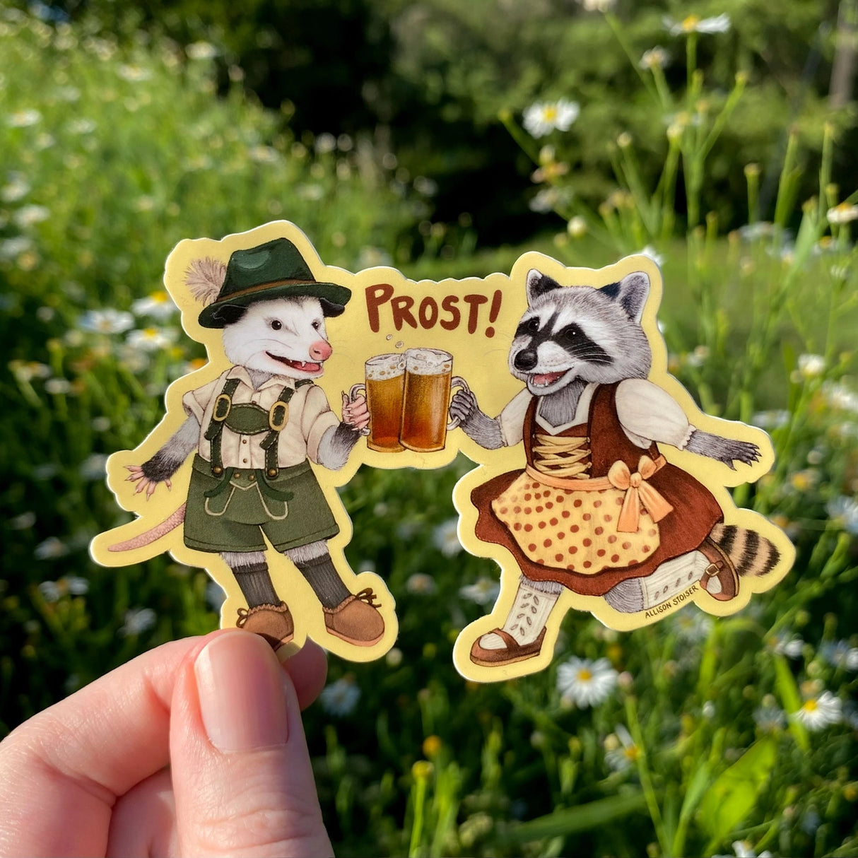 These critters are excited for Oktoberfest! Dressed in their finest lederhosen and dirndl, this opossum and raccoon are having a toast and shouting "Prost!"
This die-cut gloss vinyl sticker is durable, weatherproof, and perfect for water bottles, notebooks, laptops, bikes, and all sorts of other surfaces! Make sure to clean and dry the surface thoroughly before applying.
This sticker is perfect for folks who love opossums, raccoons, cute critters, wildlife, and Oktoberfest