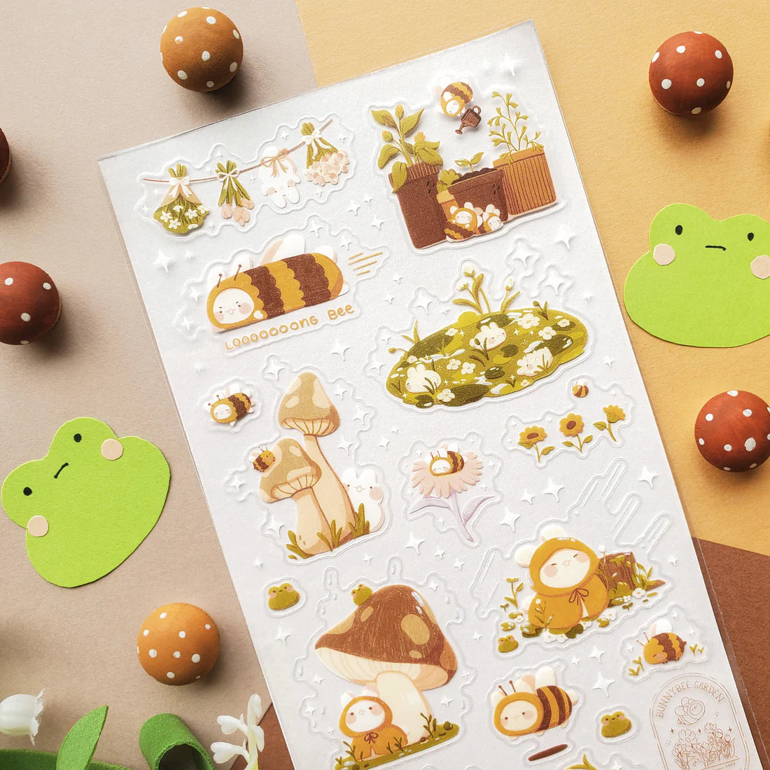 🌻🐝 Buzz on over to @bunnybee.garden’s whimsical garden, where chubby bunny-bees flutter through fields of flowers and cozy mushroom hideaways. From watering plants and zooming past blooming petals to splashing in puddles and snoozing in grassy corners, this sheet is bee-yond adorable.
Art by: @bunnybee.garden
Top Coating: None
Adhesive Layer: PVC (plastic)
Backing Layer: Clear PET
6.69" x 3.54".
Weight - 0.03lbs.
1 sheet included