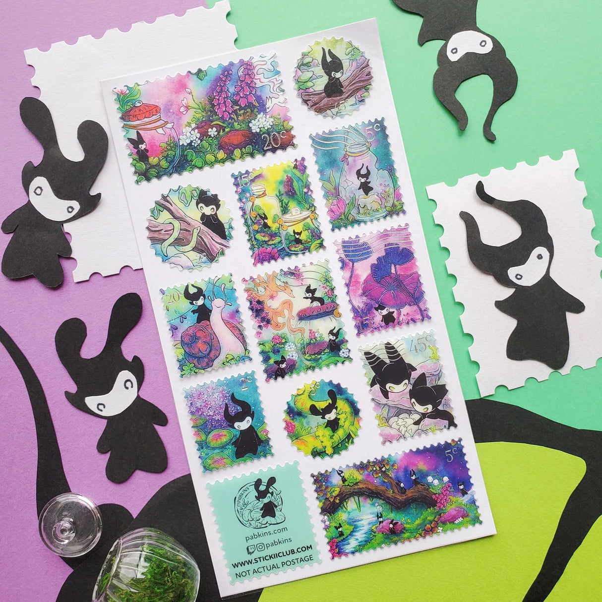 🌳🍄 Stamp your passport and hang on to it tight or one of these cuties might get curious! This whimsical sheet by @pabkins features curious little forest spirits that dart between mushrooms, bottle secret spells, ride friendly snails, and splash through ancient streams. They got a penchant for exploring, and they want you to join (sometimes unknowingly!)
Art by: @pabkins
Top Coating: Silver foil
Adhesive Layer: Paper
Backing Layer: Clear PET
6.69" x 3.54".
Weight - 0.03lbs.
1 sheet incl