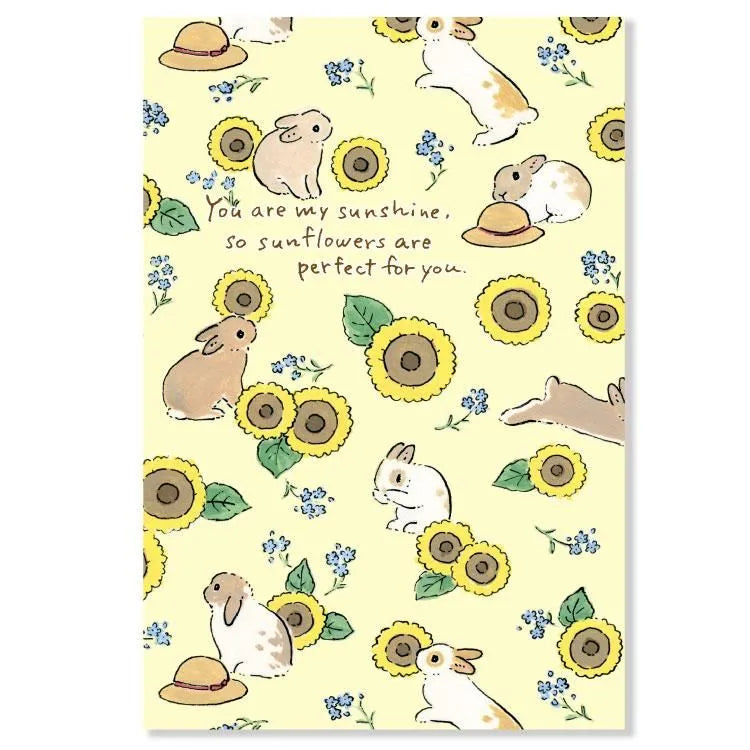 Hop into summer with this adorable postcard by Schinako Moriyama, who is known for her fun and adorable bunny scenes! This postcard features bunnies playing amongst the sunflowers.
4in x 5.8in