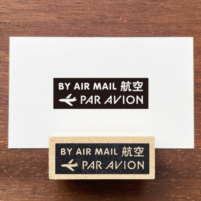 Stamp Marche Air Mail Wooden Stamp Two 'By Air Mail Par Avion' stamps on a wooden surface with a white card.