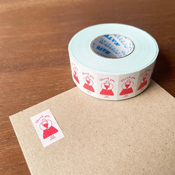 Roll of decorative tape with red designs on a wooden surface