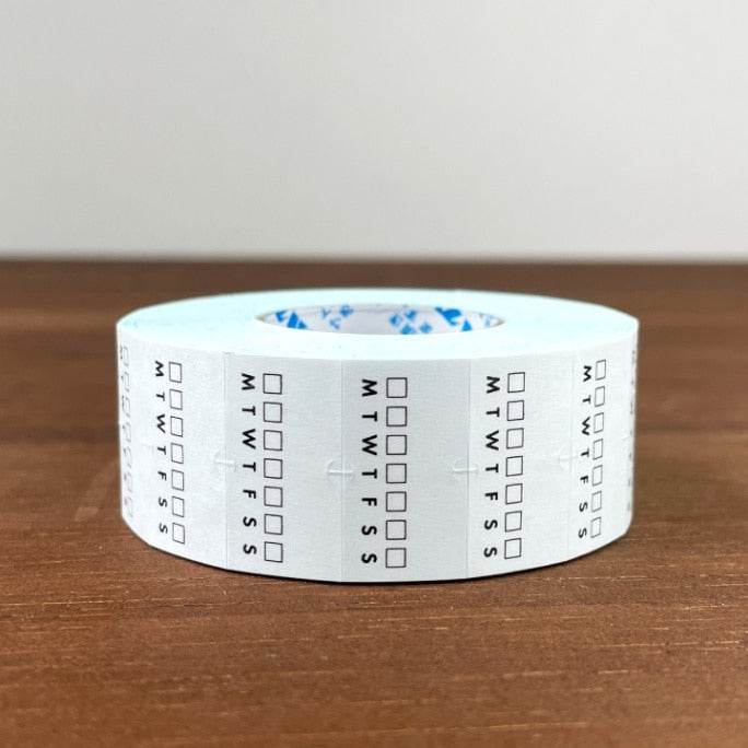 Stamp Marche Planner Label Sticker Roll - Weekly Habit Tracker Roll of tape with calendar markings on a wooden surface