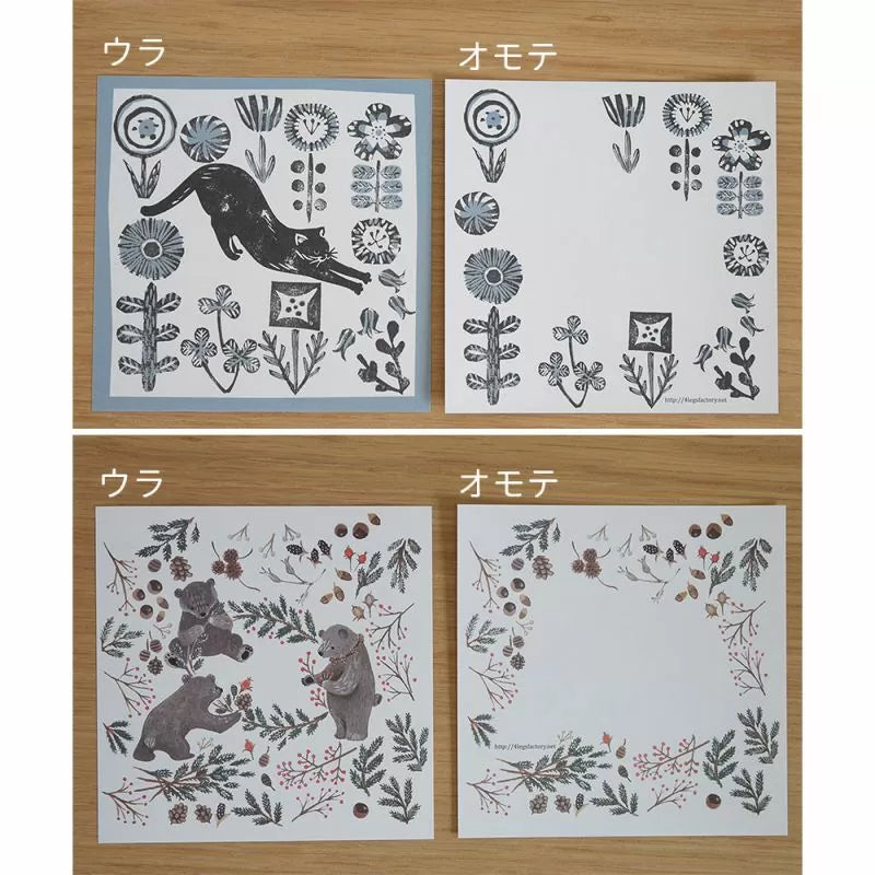Four sheets of paper with floral and animal designs on a wooden surface