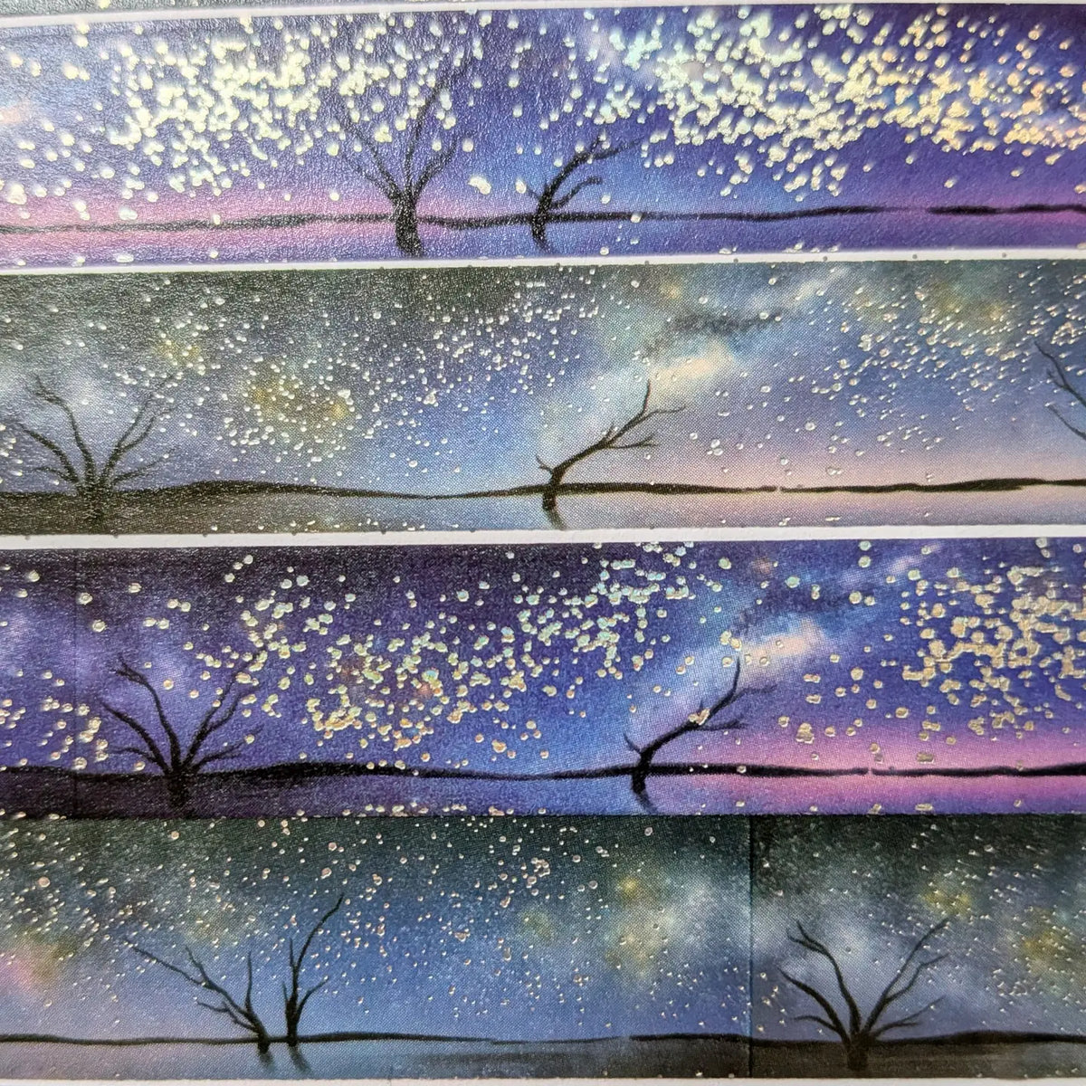 AdrianSlothArt - Holographic Foil Galaxy Washi Tape

Dreamy washi tape with holographic foil stars featuring a landscape with the milky way, tree silhouettes, and water reflections.

Details:

15 mm x 10 m
holographic foil washi tape
There are 2 versions of this design. This listing is for the more saturated version. The second version is more desaturated and has slightly darker colors.