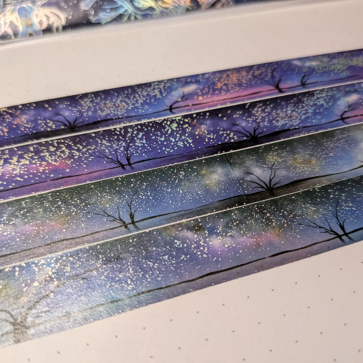 AdrianSlothArt - Holographic Foil Galaxy Washi Tape

Dreamy washi tape with holographic foil stars featuring a landscape with the milky way, tree silhouettes, and water reflections.

Details:

15 mm x 10 m
holographic foil washi tape
There are 2 versions of this design. This listing is for the more saturated version. The second version is more desaturated and has slightly darker colors.