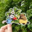 This large 4” sticker features my illustration of two little overall-clad opossum and beaver farmers picking a fresh strawberry.
