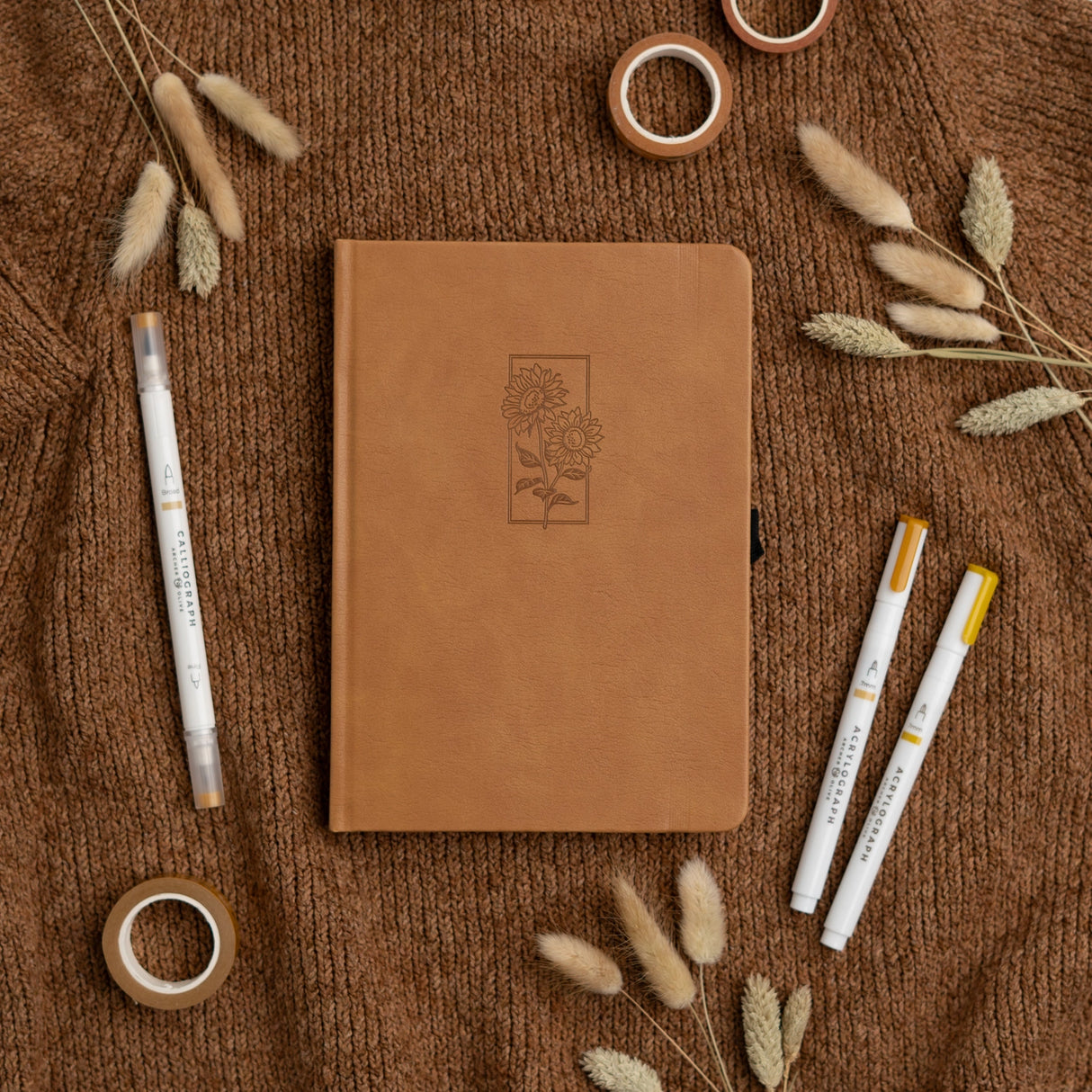 Let your ideas bloom with this warm and inviting Sunflower Notebook. Wrapped in a rich caramel vegan leather cover, it features a beautifully debossed pair of sunflowers—symbols of joy, hope, and creative energy. Whether you're journaling your thoughts or planning your next big project, this notebook brings a little sunshine to every page.

✨&nbsp;Features You’ll Love

Elegant debossed sunflower illustration&nbsp;for a clean, understated botanical look

Caramel vegan leather cover&nbsp;that’s soft to the to