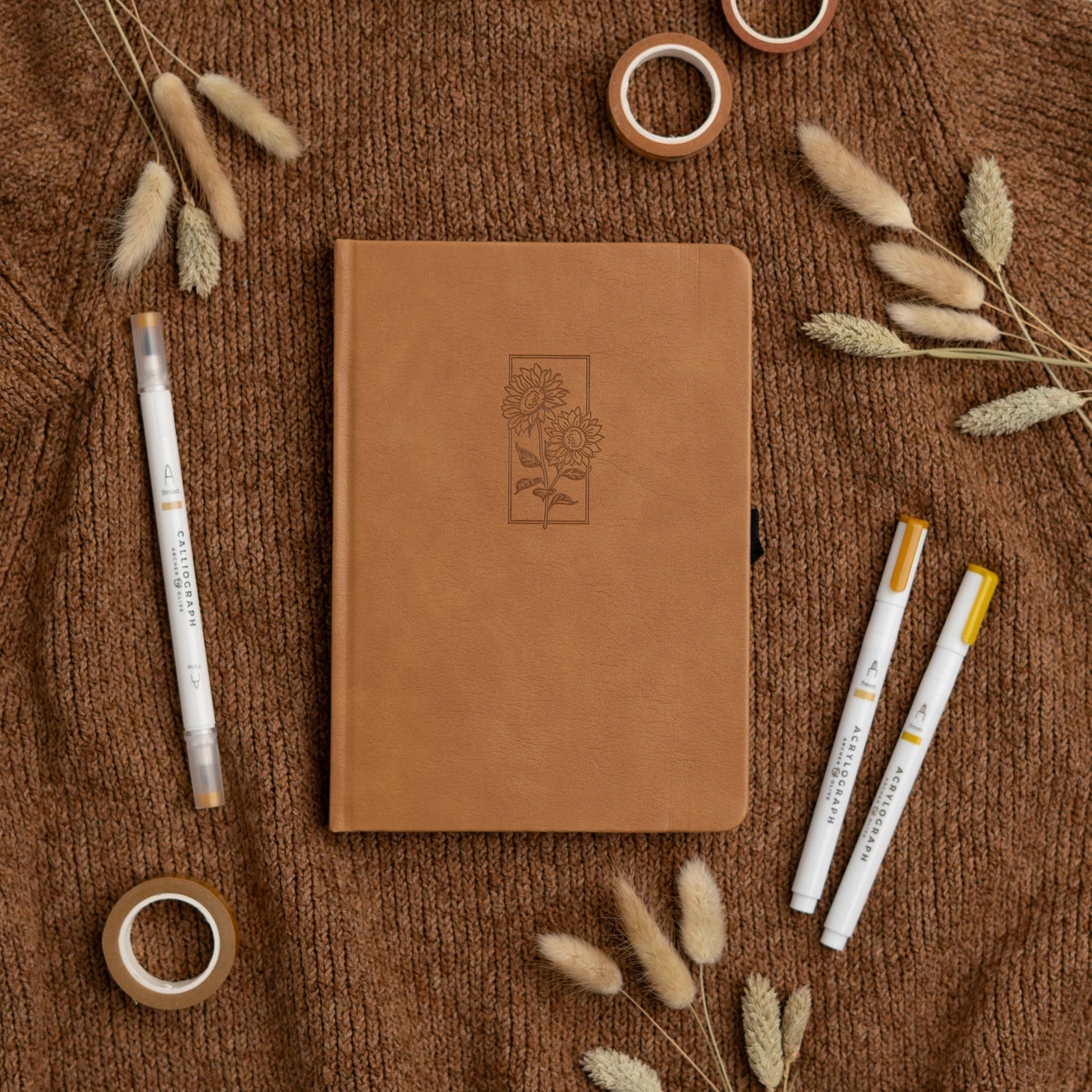 Let your ideas bloom with this warm and inviting Sunflower Notebook. Wrapped in a rich caramel vegan leather cover, it features a beautifully debossed pair of sunflowers—symbols of joy, hope, and creative energy. Whether you're journaling your thoughts or planning your next big project, this notebook brings a little sunshine to every page.

✨&nbsp;Features You’ll Love

Elegant debossed sunflower illustration&nbsp;for a clean, understated botanical look

Caramel vegan leather cover&nbsp;that’s soft to the to